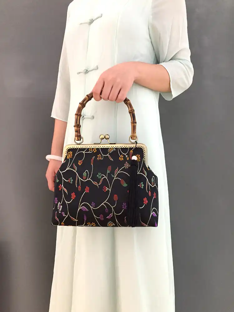 Close-up view of intricate floral embroidery pattern on luxury satin clutch bag.