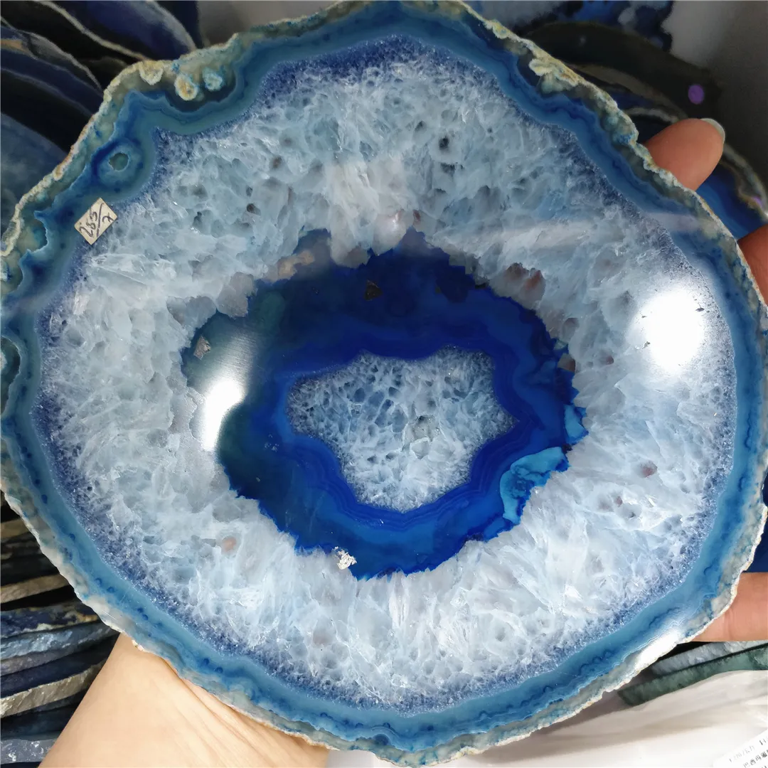 Single blue agate slice coaster on white background highlighting natural rough crystal edges.