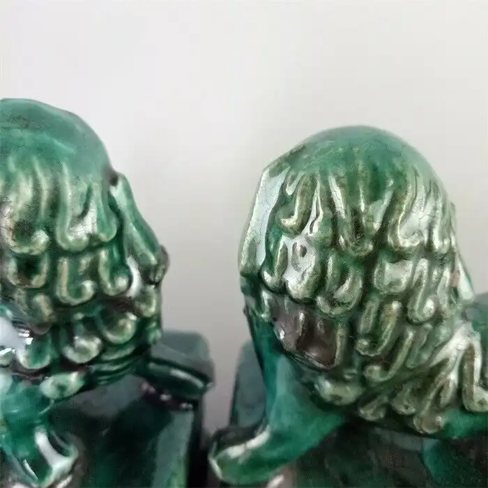 Chinese green glaze porcelain foo dog statues pair showing traditional guardian lion design with antique finish.