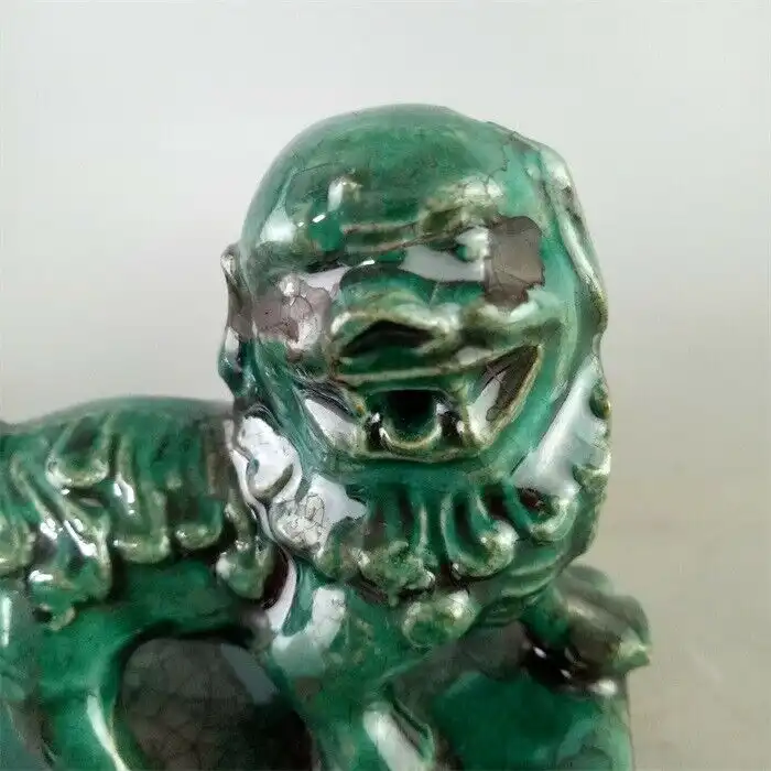 Close-up detail of foo dog statue face featuring expressive eyes, flowing mane, and protective guardian expression.