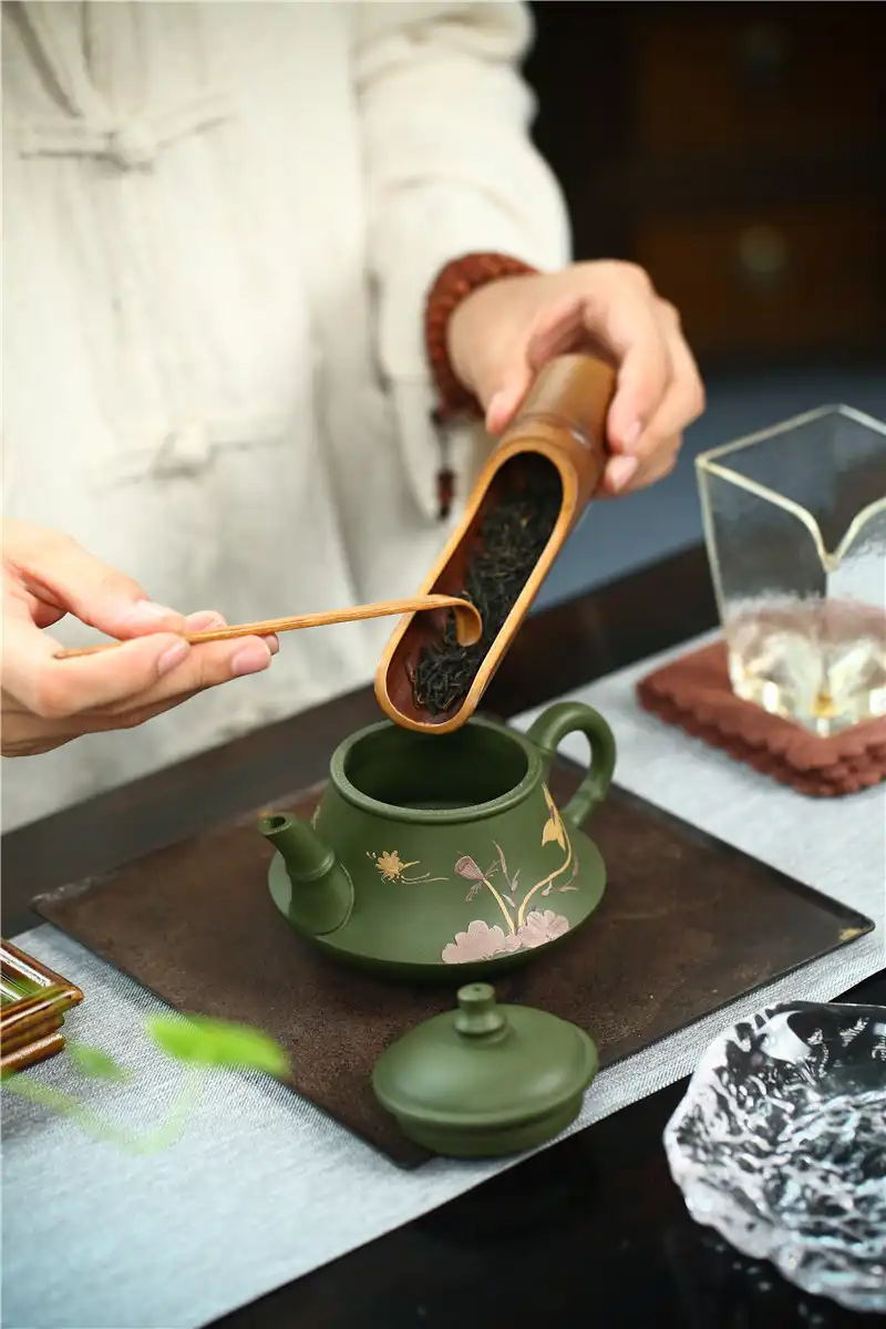 Folk artist crafting authentic green mud teapot using traditional Yixing pottery techniques.