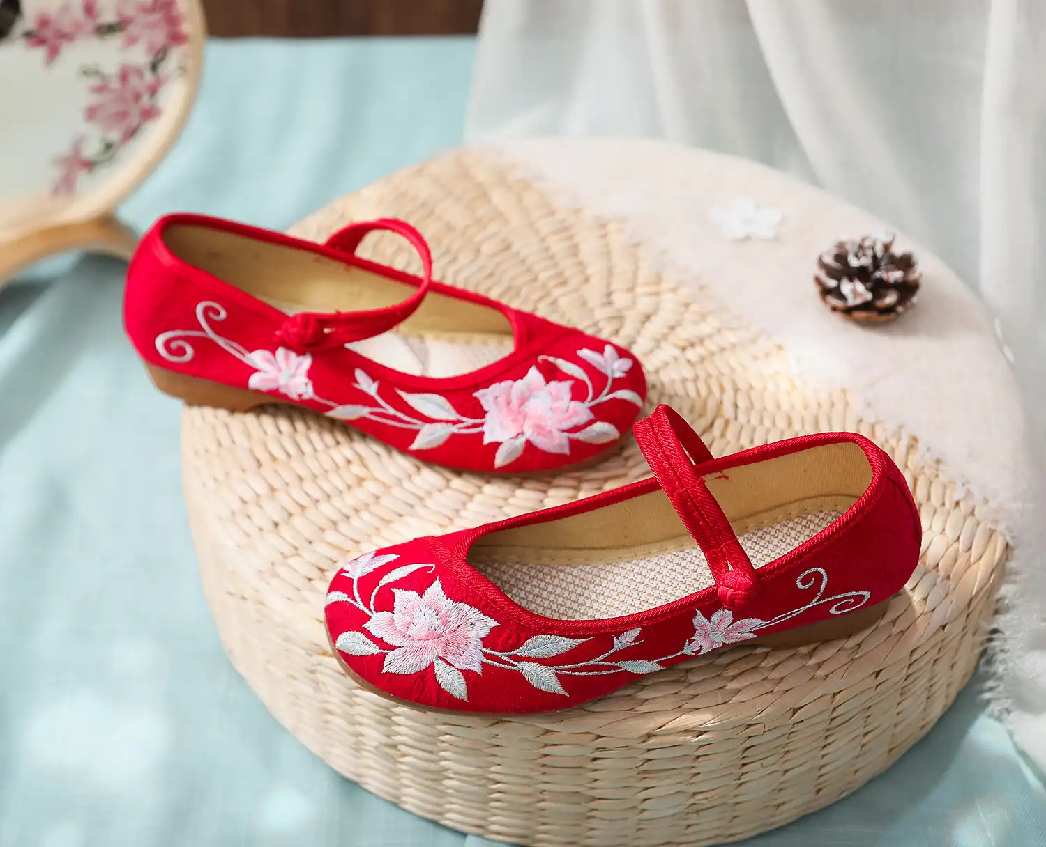 Pair of embroidered kung fu flats arranged on traditional Chinese silk fabric background.
