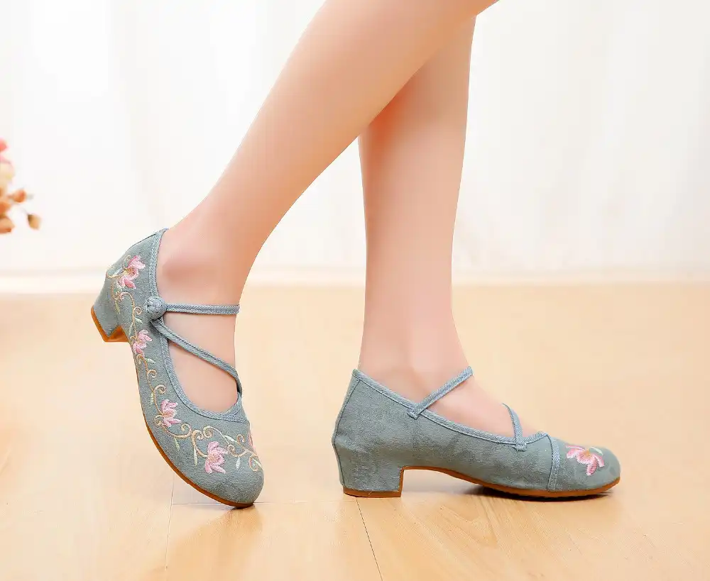 Pair of embroidered kung fu pumps arranged on traditional Chinese fabric background.