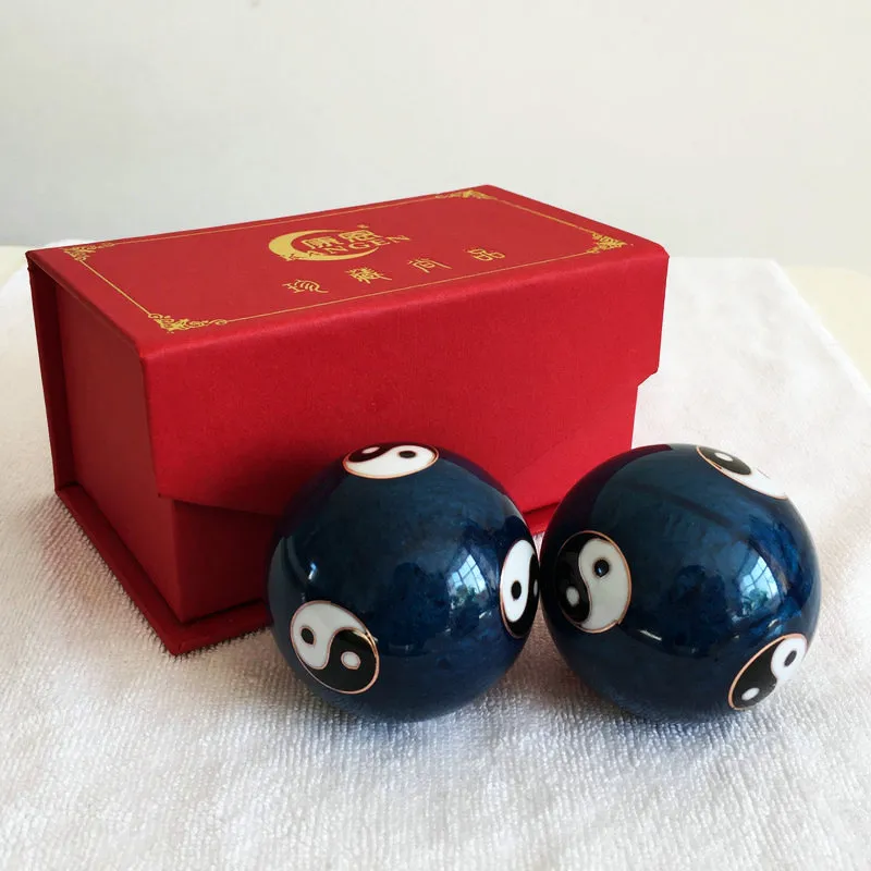 Close-up view of traditional Chinese Baoding balls showing intricate white plum flower pattern detail.