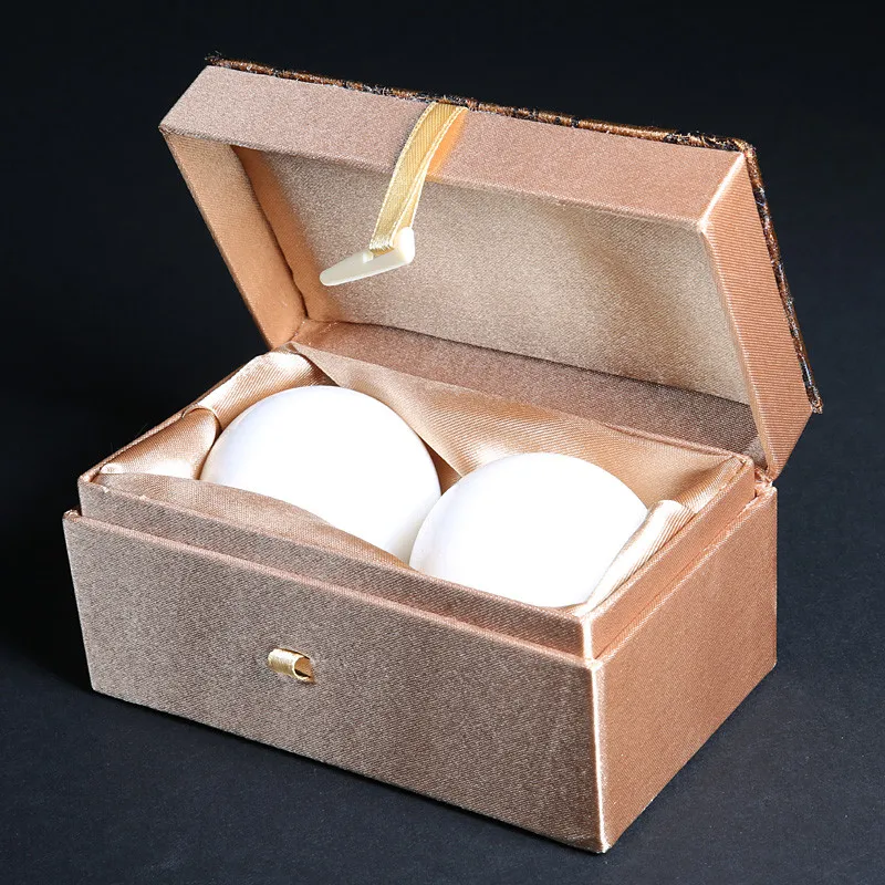 Jade therapy balls in hands demonstrating proper rotation technique for stress relief and hand exercise.