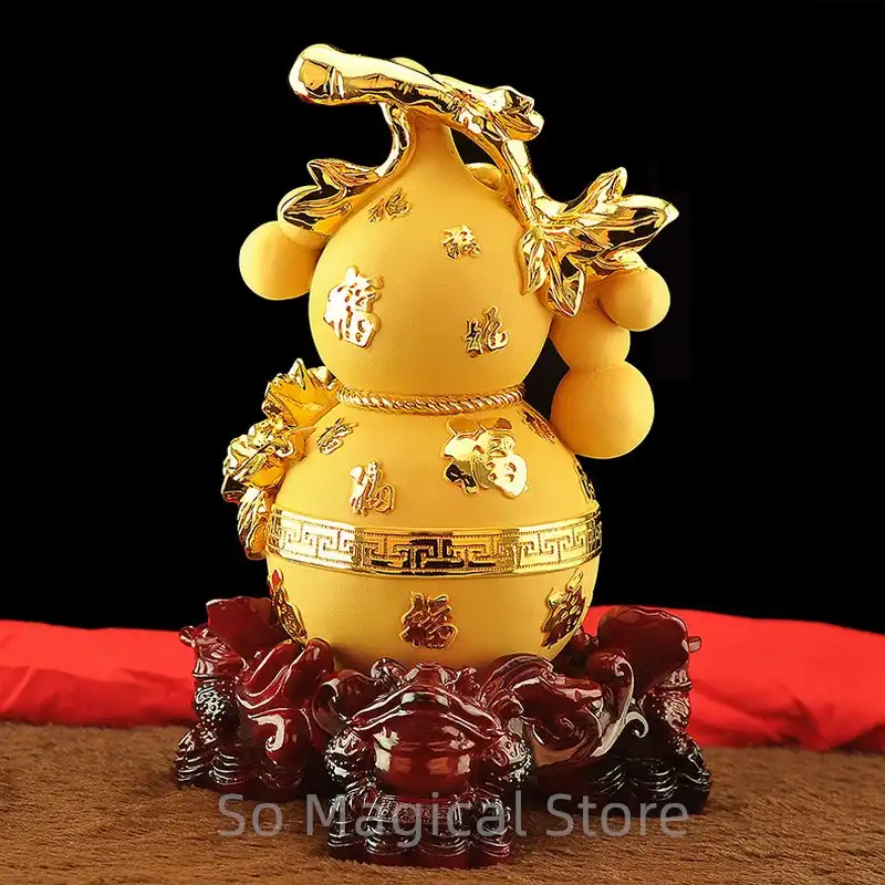 Golden wu lou ornament displayed on wooden shelf with other feng shui decorations.