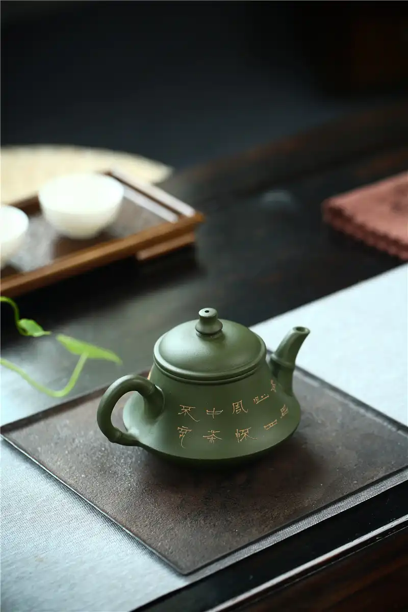 Handmade Kung Fu teapot spout and handle detail displaying smooth green mud surface and ergonomics.