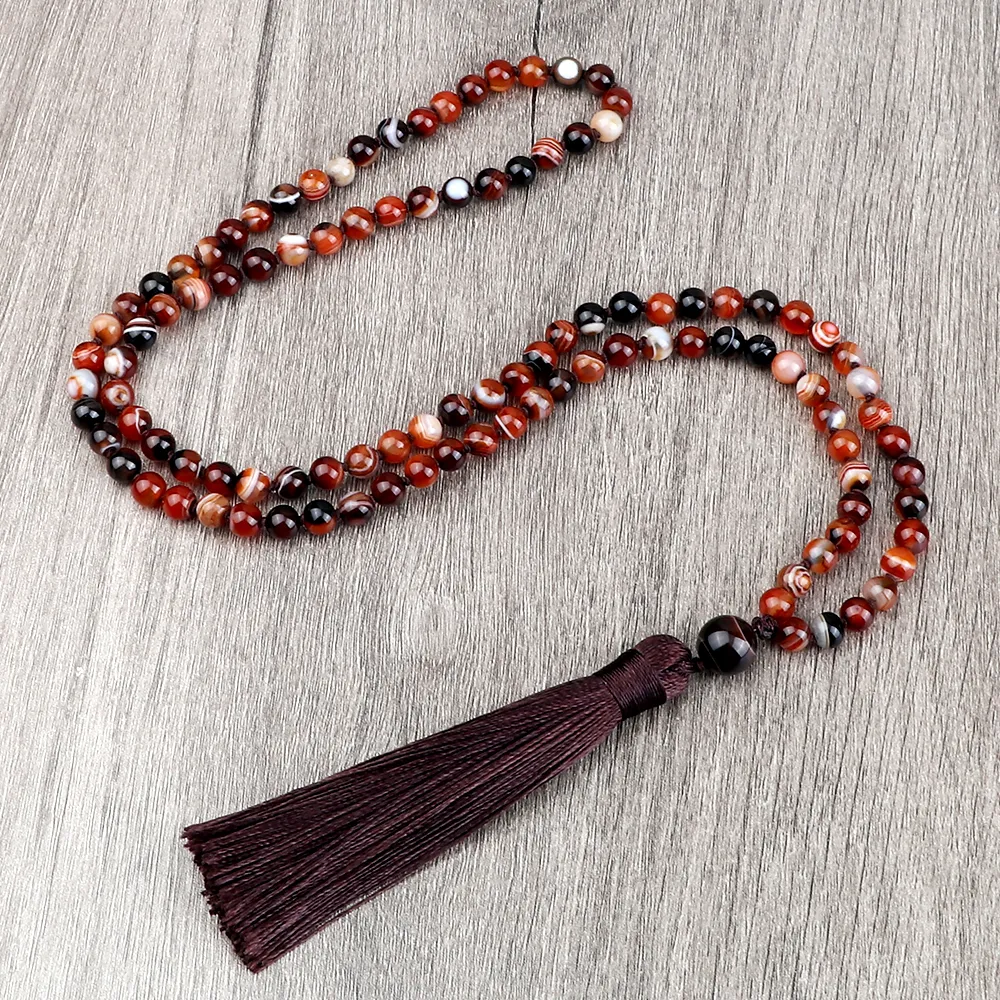 Hands holding 108 bead mala necklace during meditation and spiritual prayer practice.