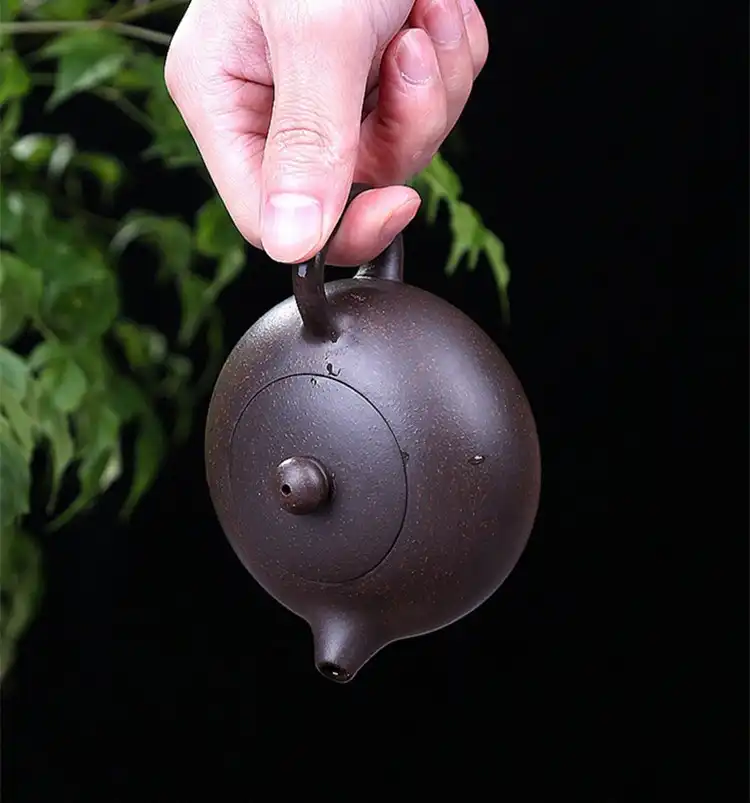 Traditional Chinese tea ceremony setup featuring handmade Xishi purple clay teapot as centerpiece.