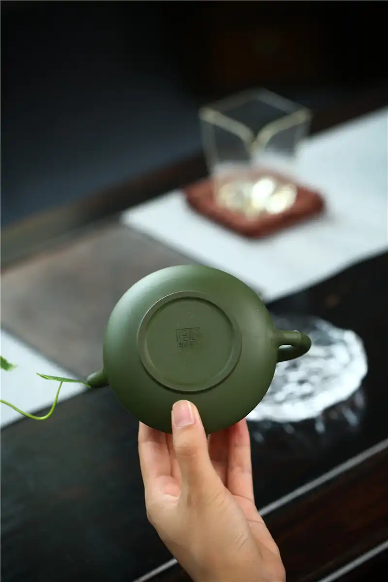 Puer tea brewing process using handmade green mud teapot showing golden tea color and clarity.