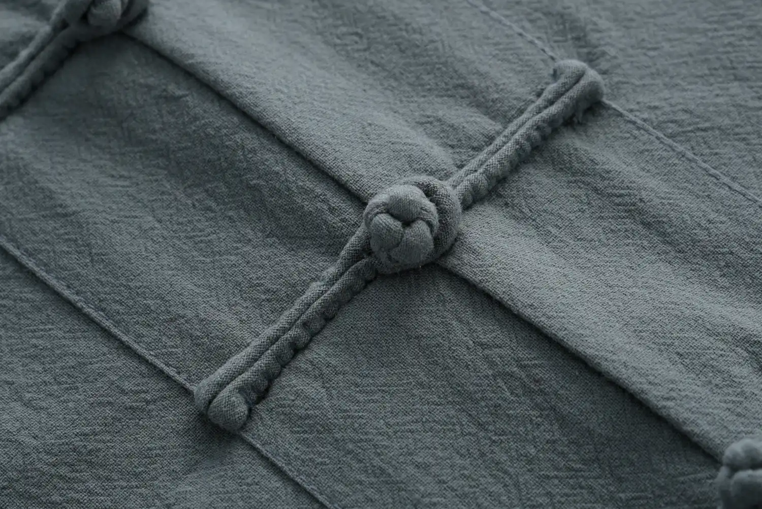 Close-up view of traditional Chinese frog button details on cotton tang suit sleeve.