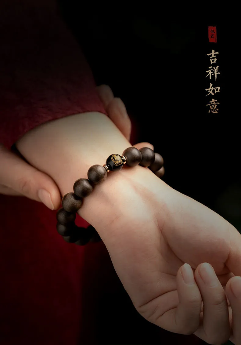 Hands holding natural agarwood Buddha zodiac bracelet showing size and bead quality detail.