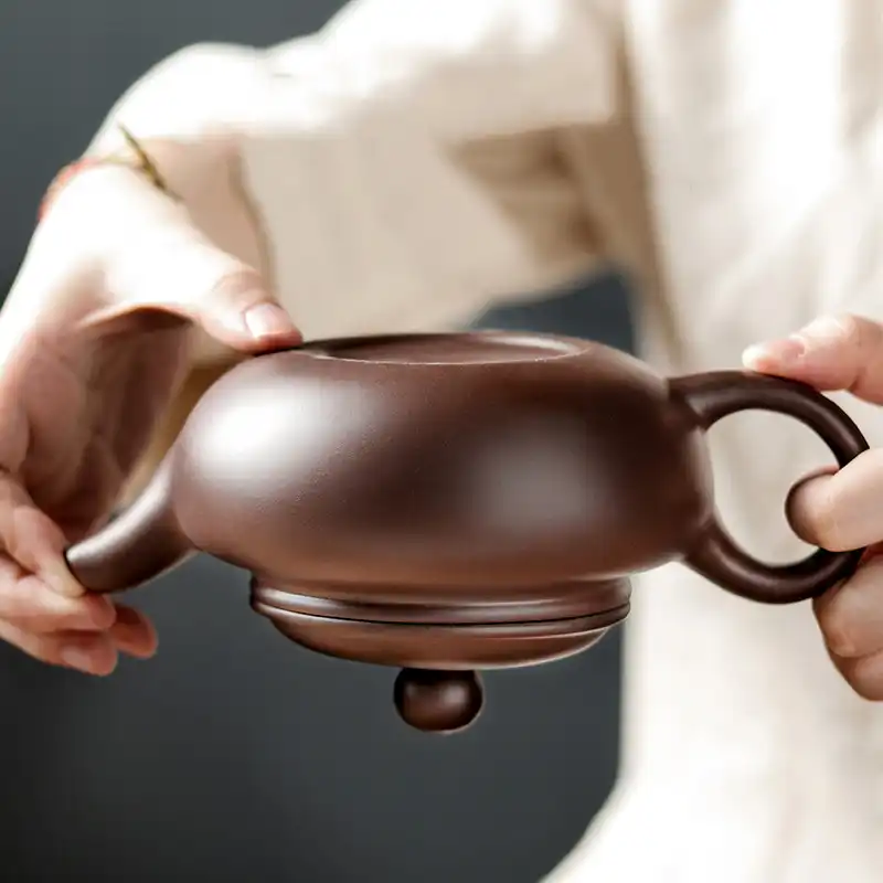 Purple clay teapot in use demonstrating smooth tea pouring technique and controlled flow.