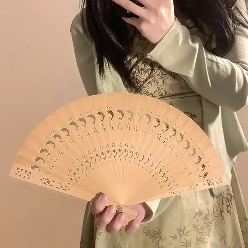 Chinese wooden carved folding hand fan with sandalwood scent and hollow wood design patterns.