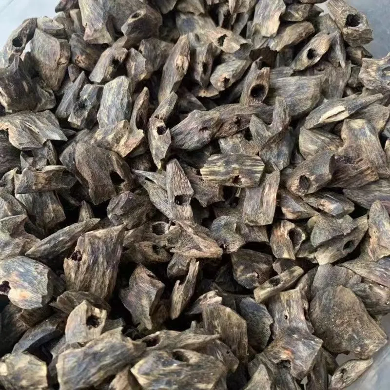 ​​Premium Vietnamese agarwood chips displayed in wooden bowl showing natural texture and color.