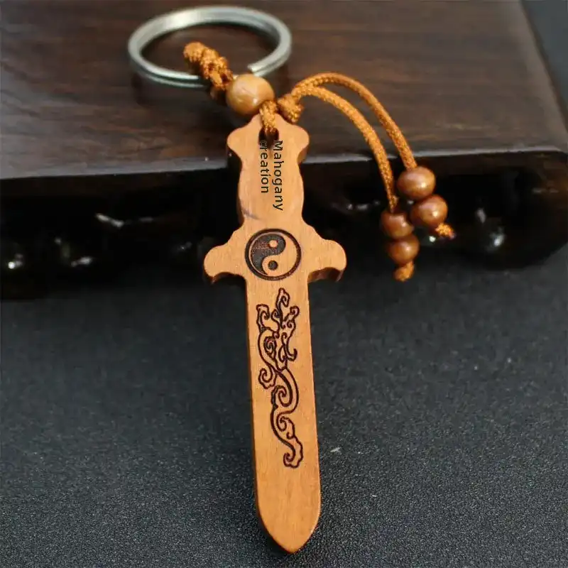 Handcrafted peach wood sword car keychain with antique engraving artwork and natural wood grain.