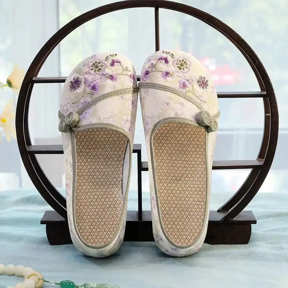 Pair of traditional Chinese embroidered shoes arranged on wooden surface with cultural elements.