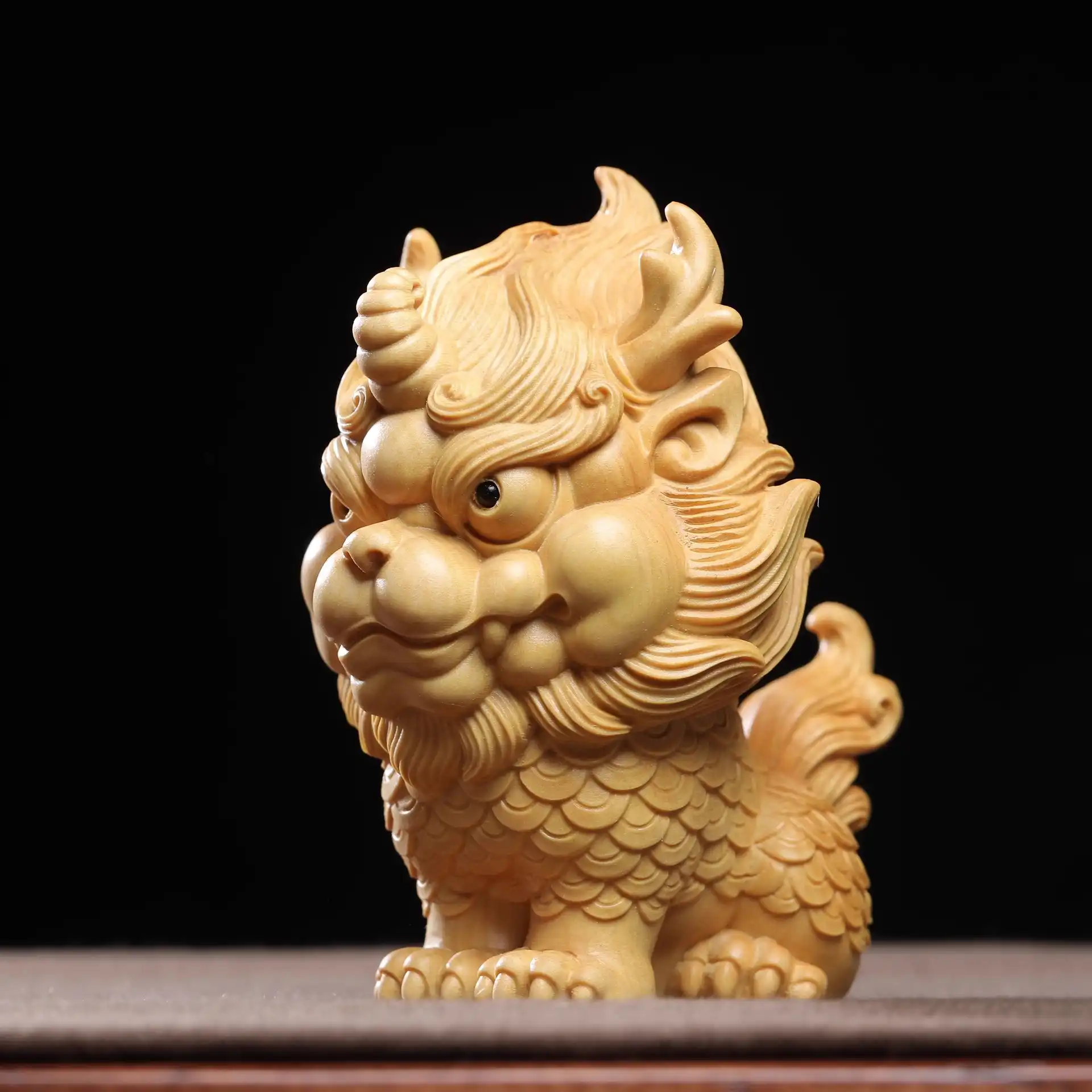 Miniature wooden Qilin carving ornament showing intricate hand-carved details and natural wood finish.