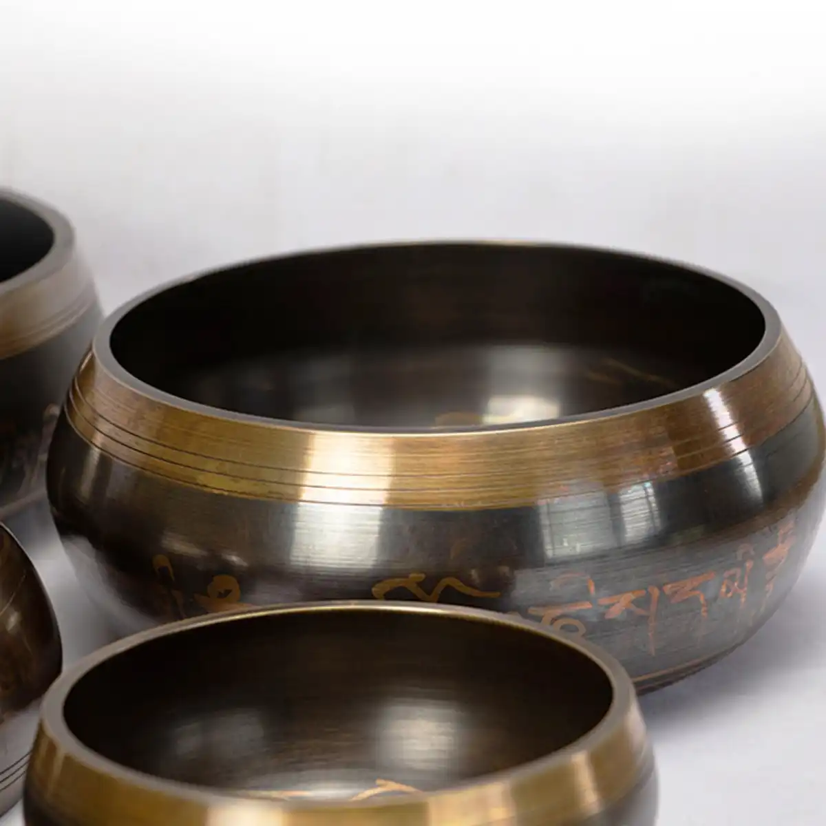 Hands gently striking singing bowl rim creating peaceful vibrations for chakra healing.