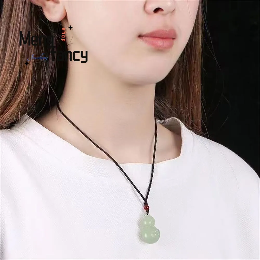 Natural jade gourd pendant with certificate of authenticity displayed beside fine jewelry piece.