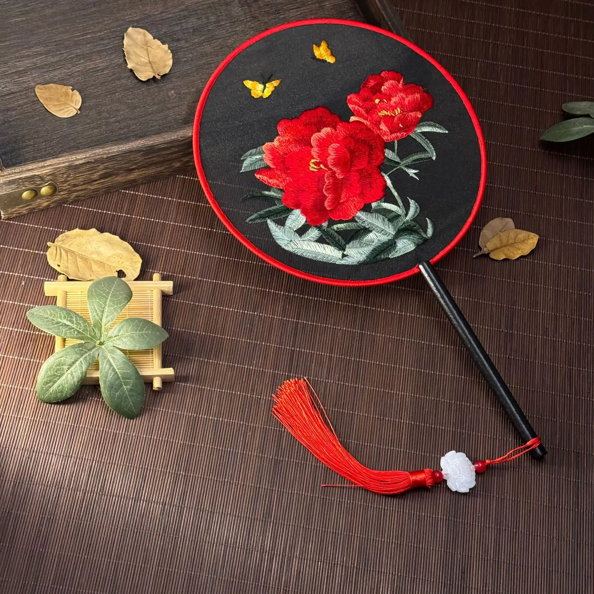 Foldable embroidered fan in closed position demonstrating compact portable design.