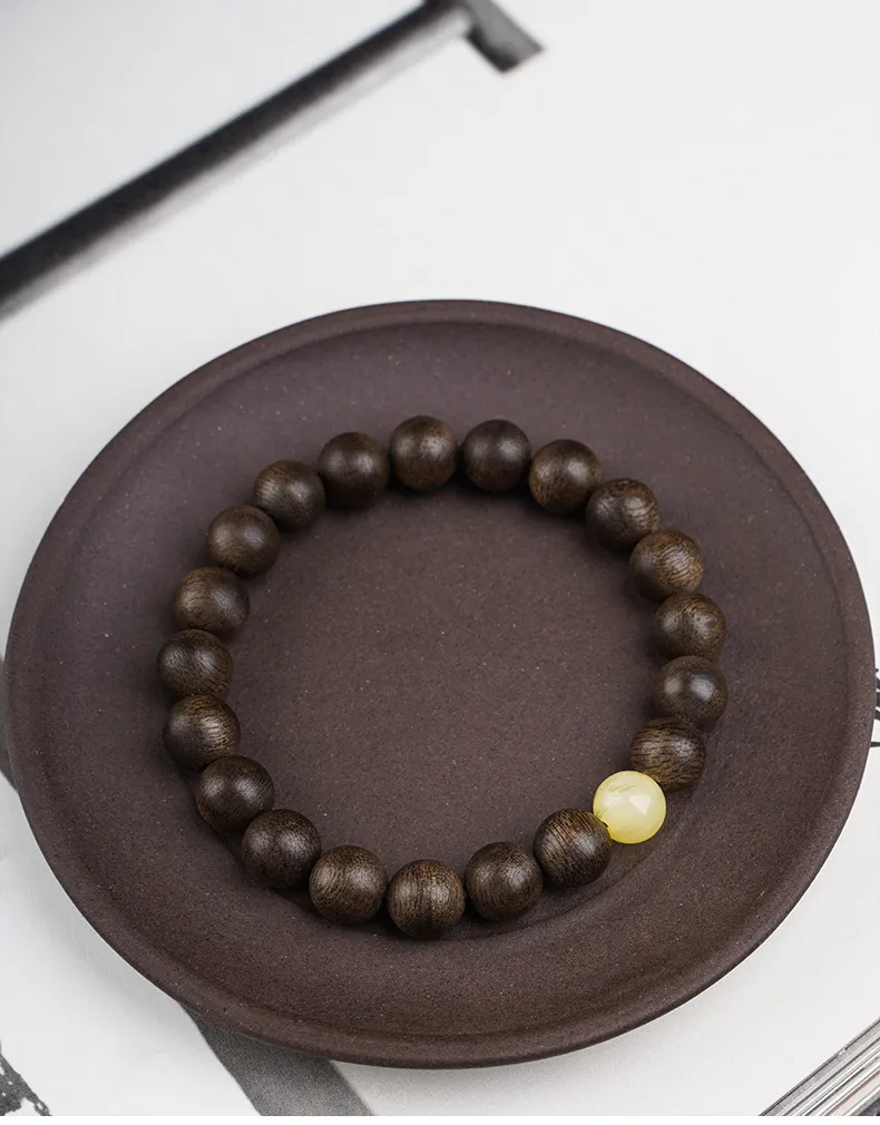 Natural Kyara agarwood prayer bracelet with polished wooden beads on white background.
