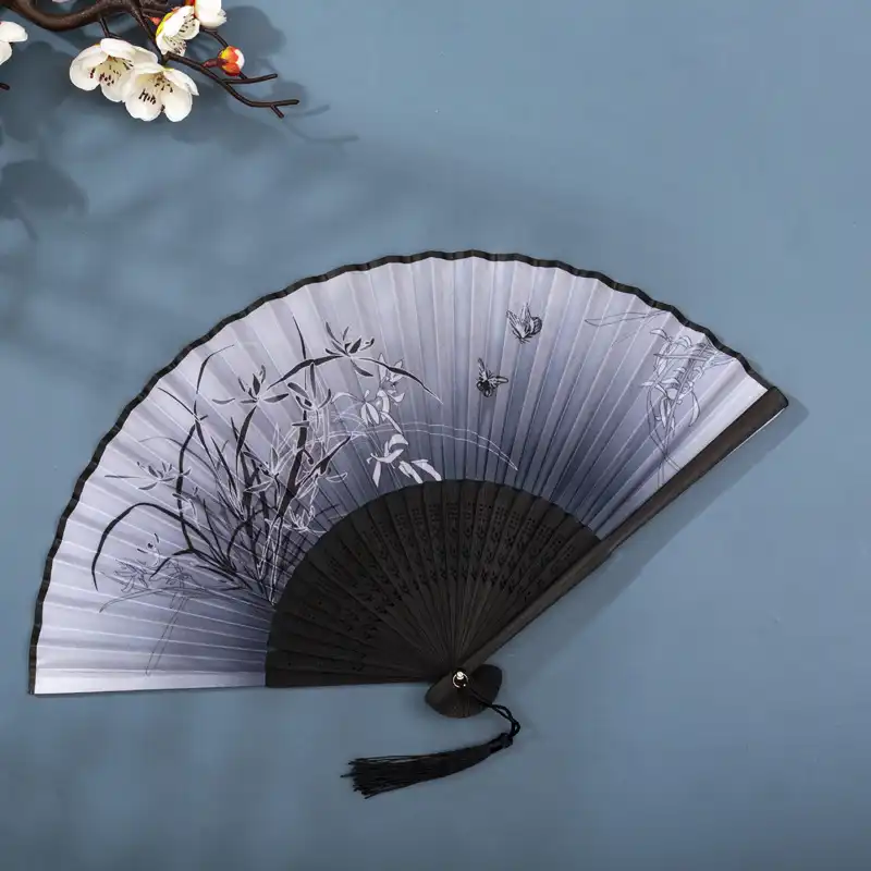 Hand holding opened silk fan demonstrating proper grip and graceful positioning technique.