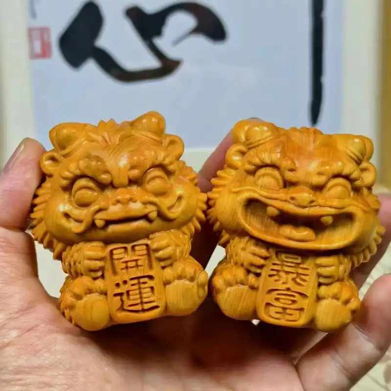 Close-up view of carved wooden guardian lion statue displaying intricate facial features and smooth finish.