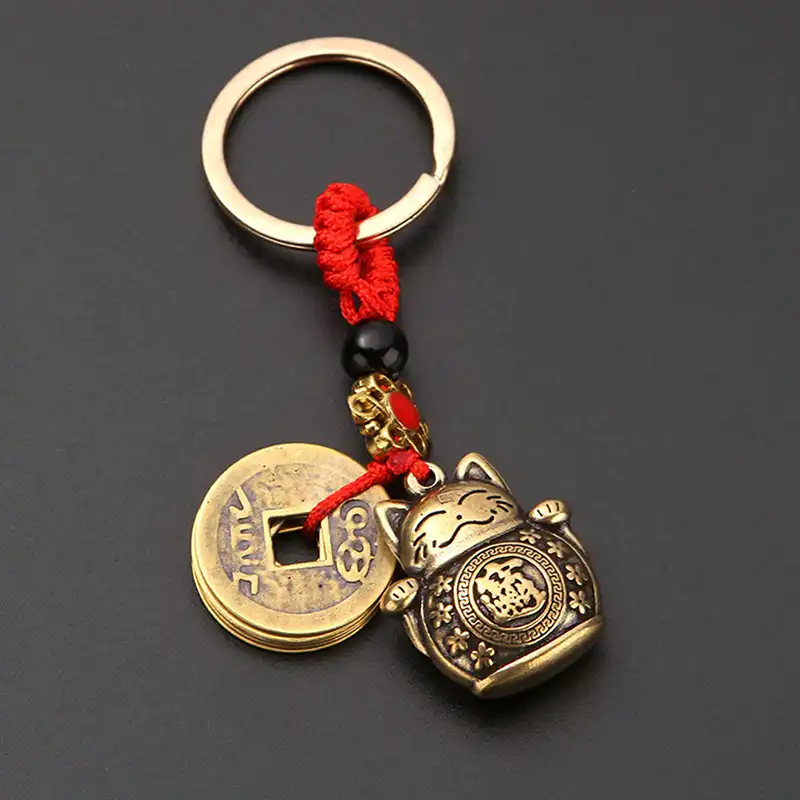 Close-up view of fortune cat figure and authentic five emperor coins on keychain.