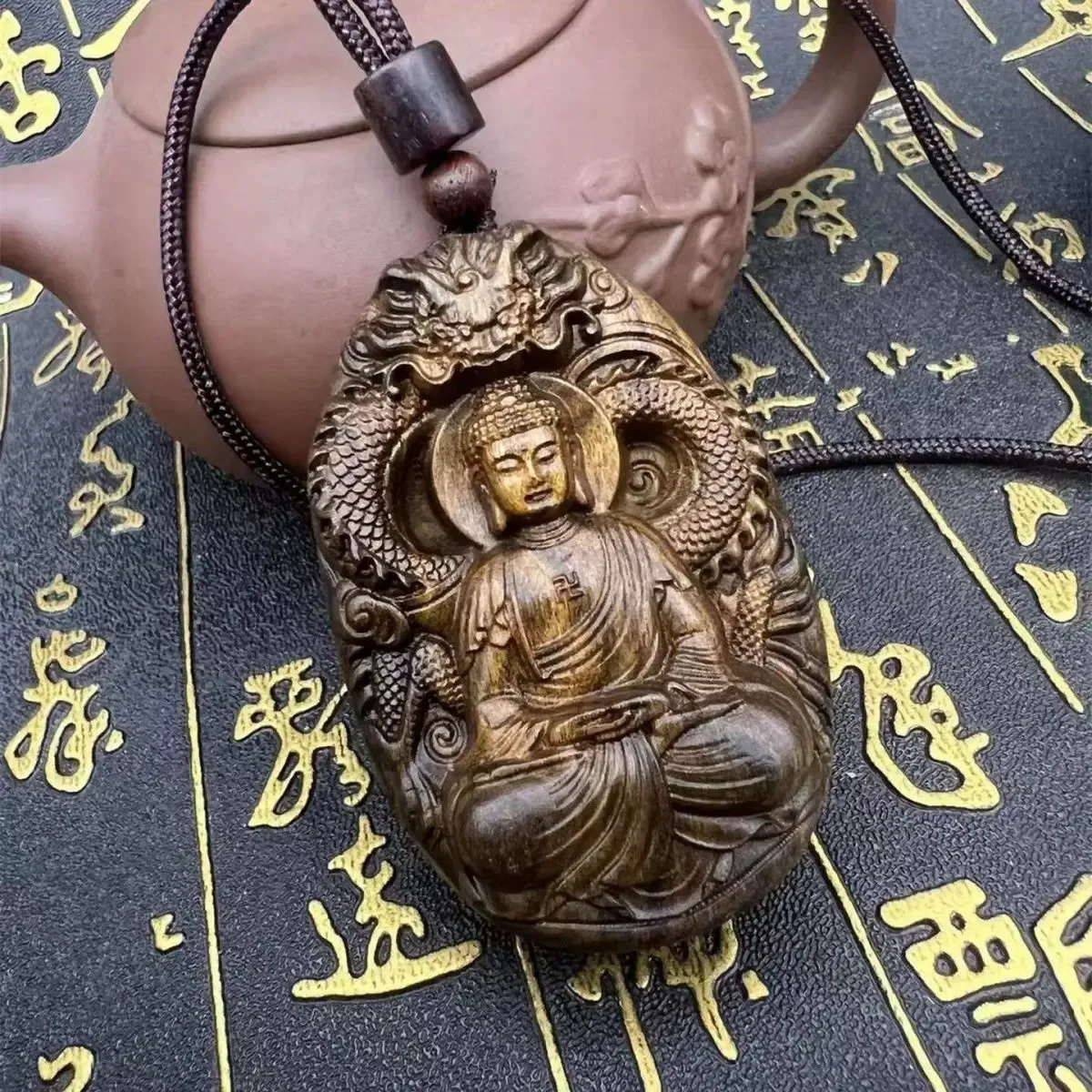 Close-up natural sandalwood wood grain texture on carved Tathagata Buddha face pendant detail.