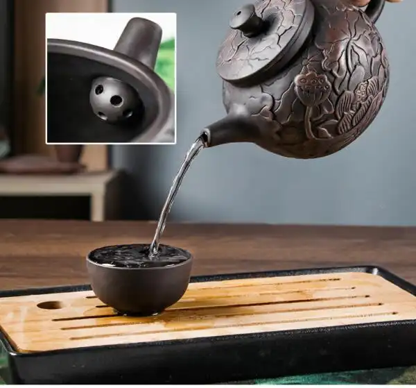 Traditional Chinese tea ceremony setup featuring hand carved lotus illustration purple clay teapot.