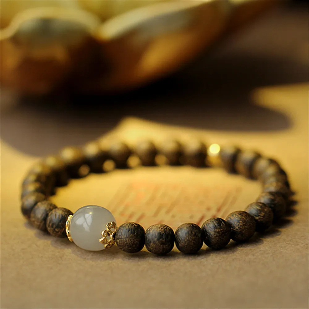 Natural Vietnam Nha Trang agarwood Buddha bracelet with Hetian jade beads and 14K gold accents on white.