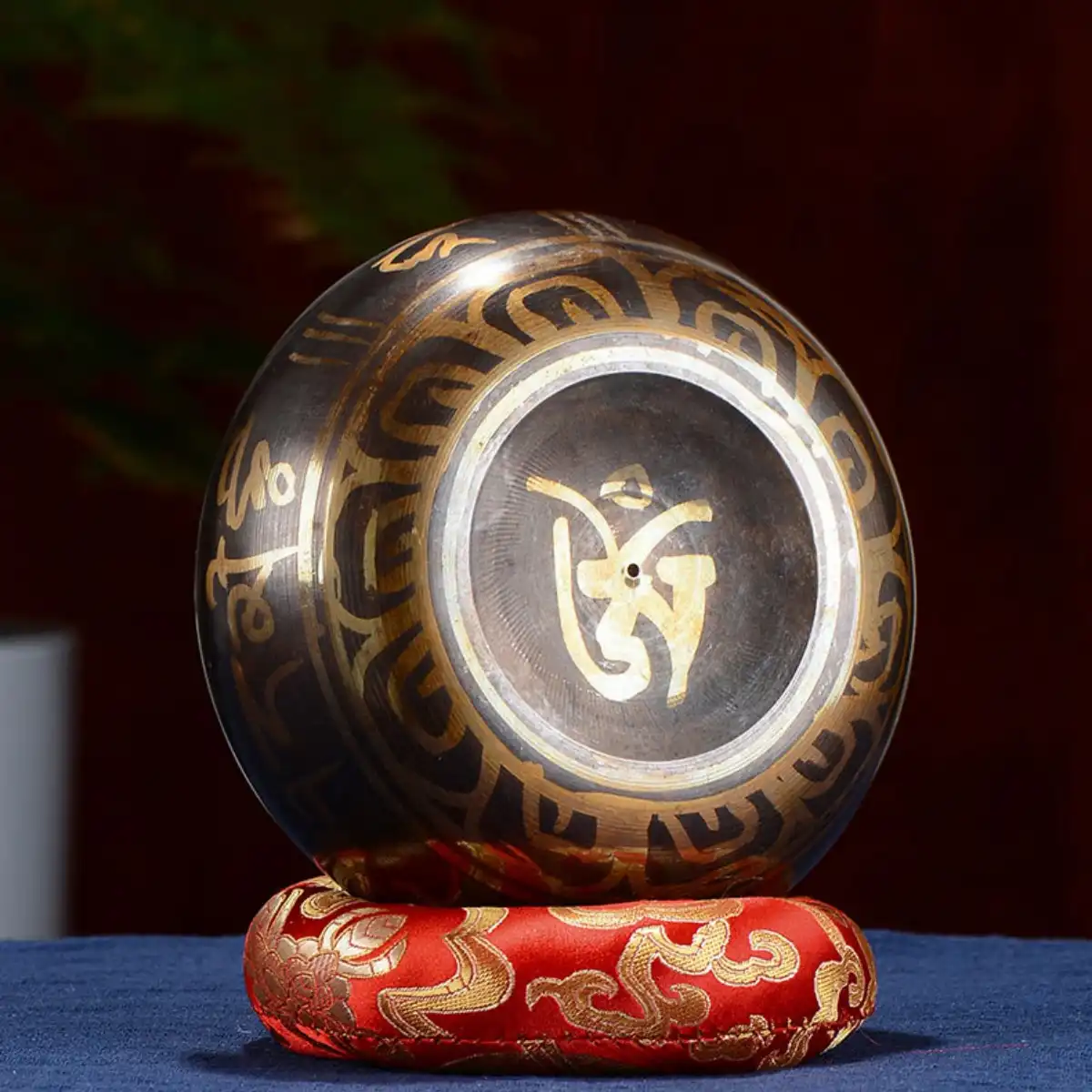 Complete singing bowl set with leather striker and colorful cushion on white background.