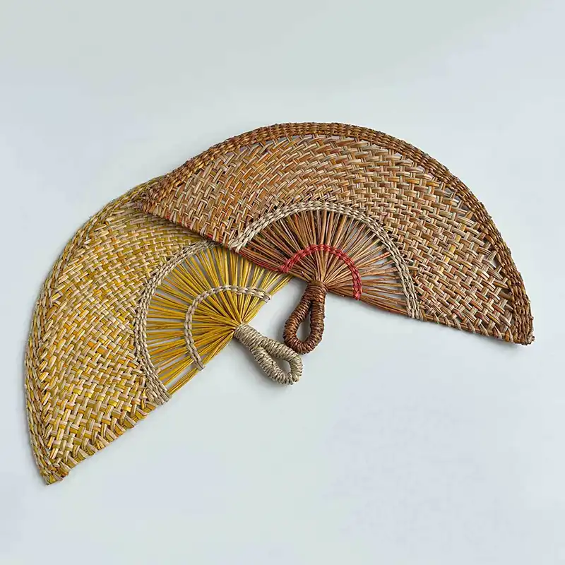 Multiple handwoven straw fans arranged showing traditional weaving variations and natural colors.