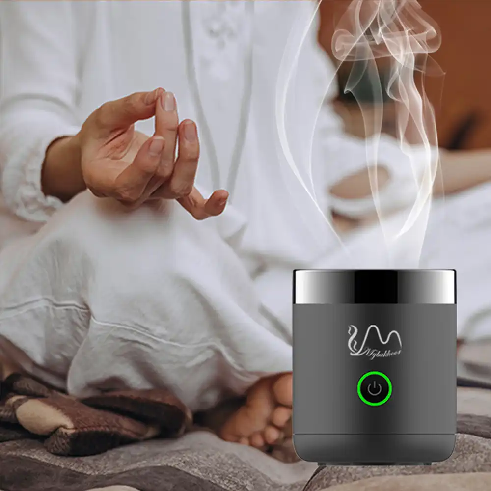 Mini portable burner heating bakhoor incense with visible aromatic smoke rising.
