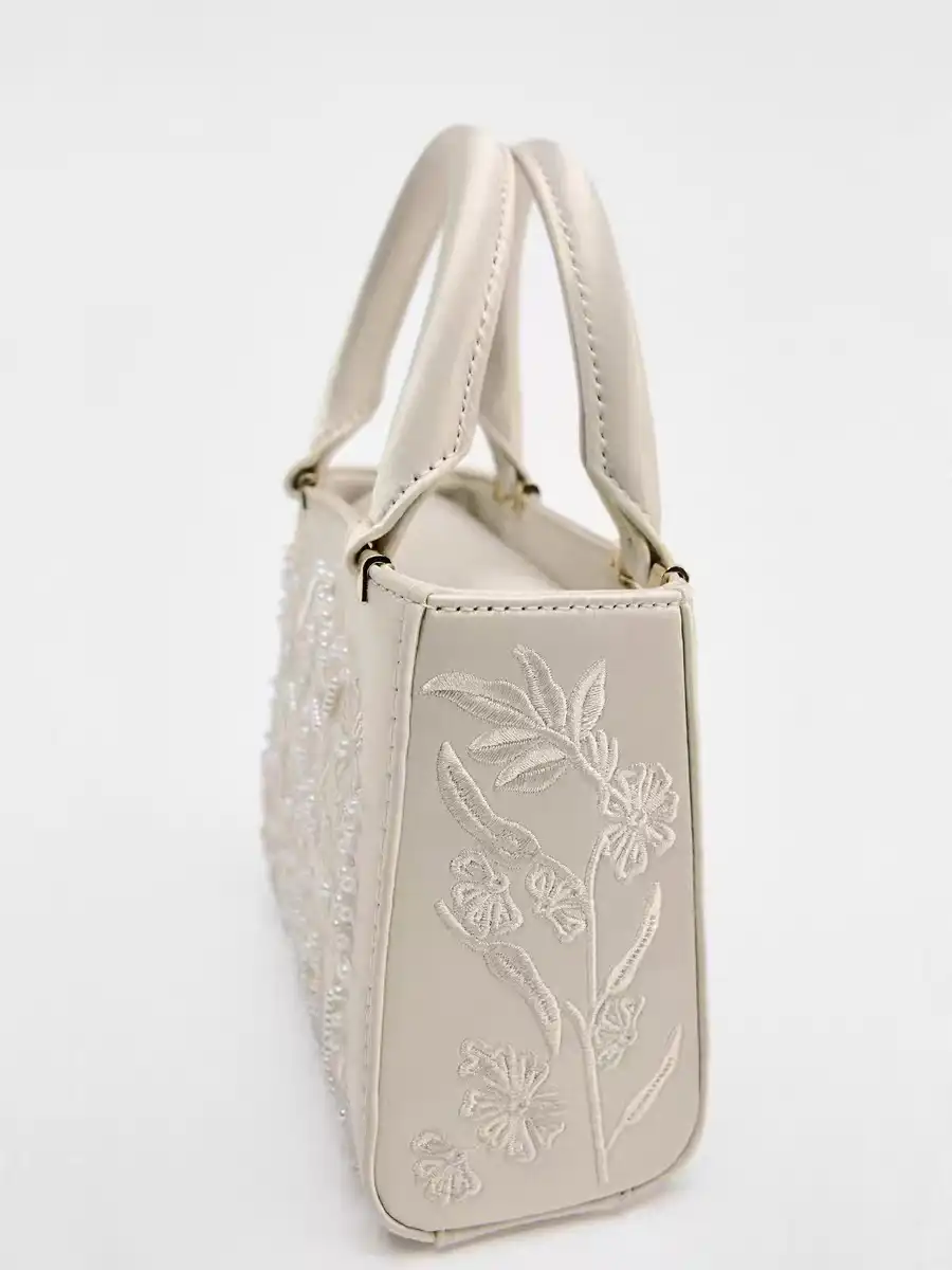 Close-up view of exquisite floral embroidery pattern on luxury women's handbag showing craftsmanship.