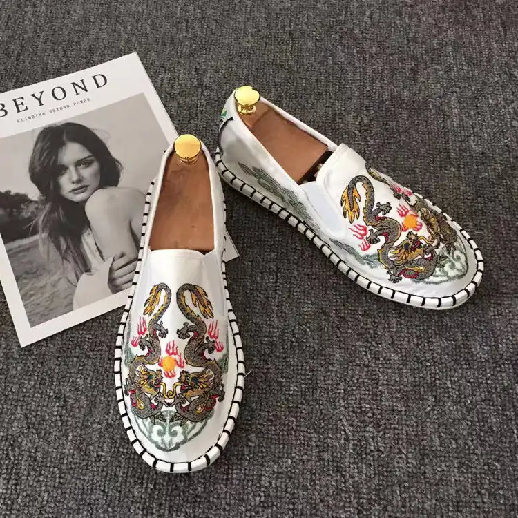 Pair of traditional Chinese cloth shoes arranged on wooden surface displaying cultural design.