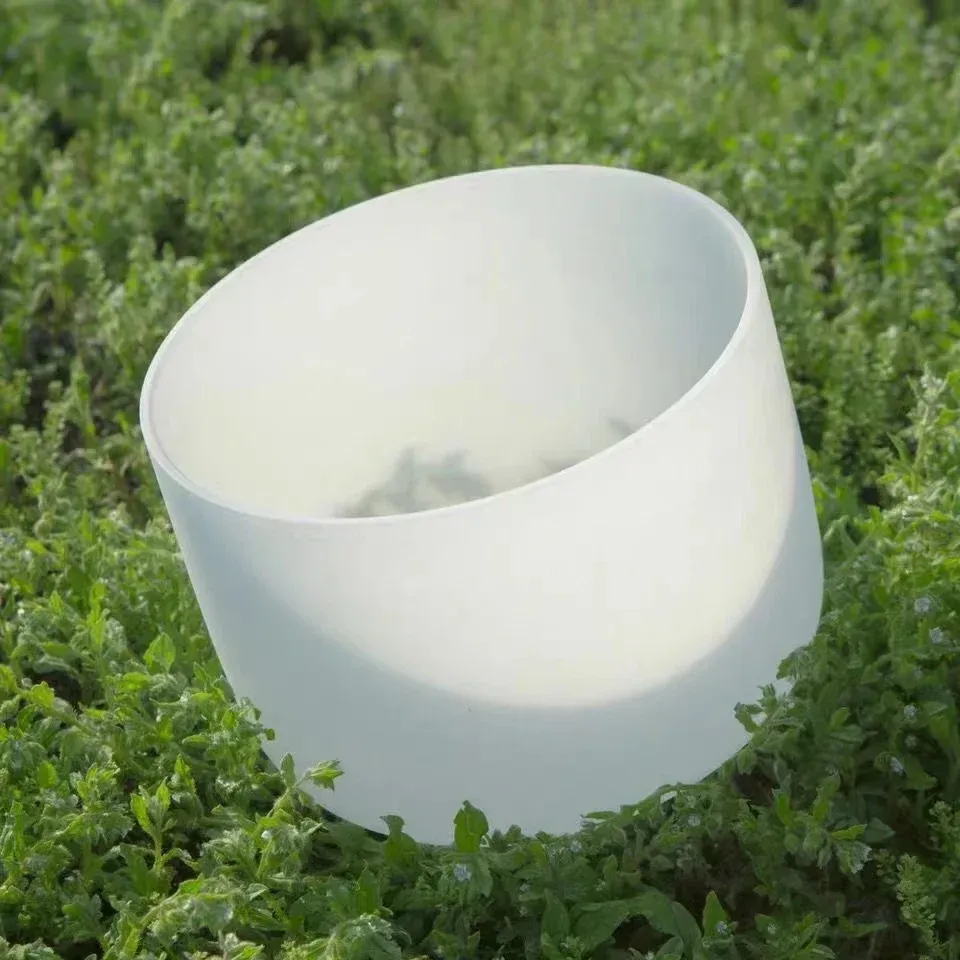 Woman using crystal singing bowl for yoga meditation and sound healing therapy session.
