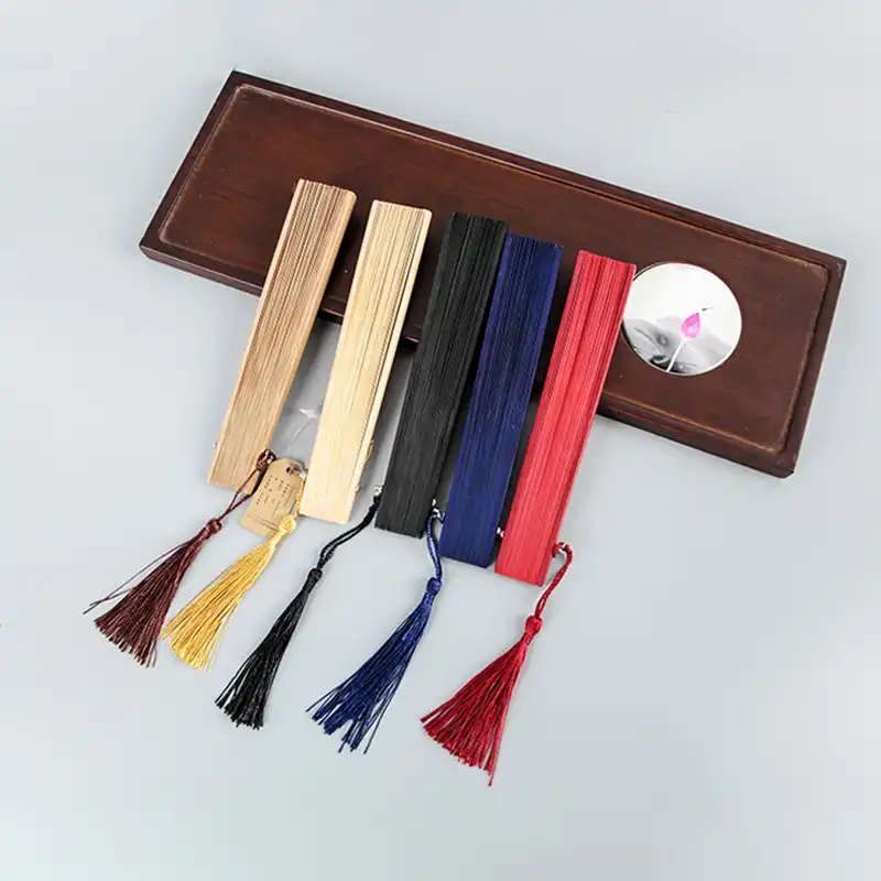 Classical Chinese small bamboo fan opened displaying plain design and tassel ornament decoration.