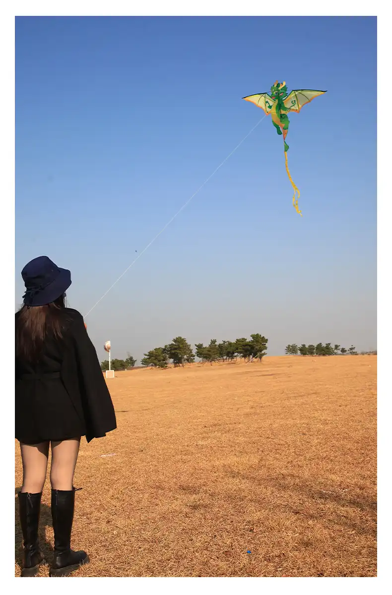 Green Chinese dragon kite soaring majestically in blue sky showing traditional design details.