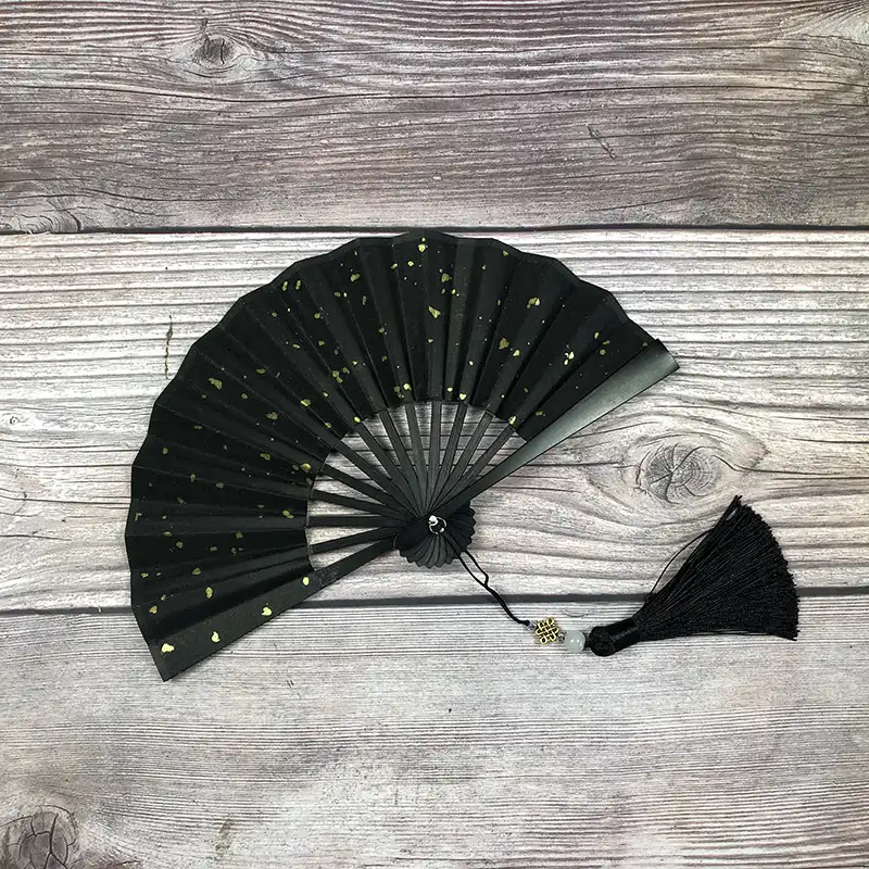 Japanese rice paper folding fan in dark green color with gilded details showing wood construction.