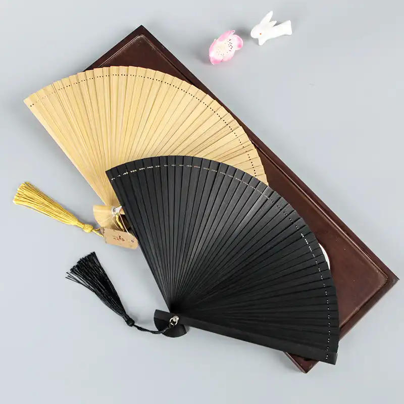 Hand holding opened plain bamboo fan demonstrating proper dance performance grip and positioning.
