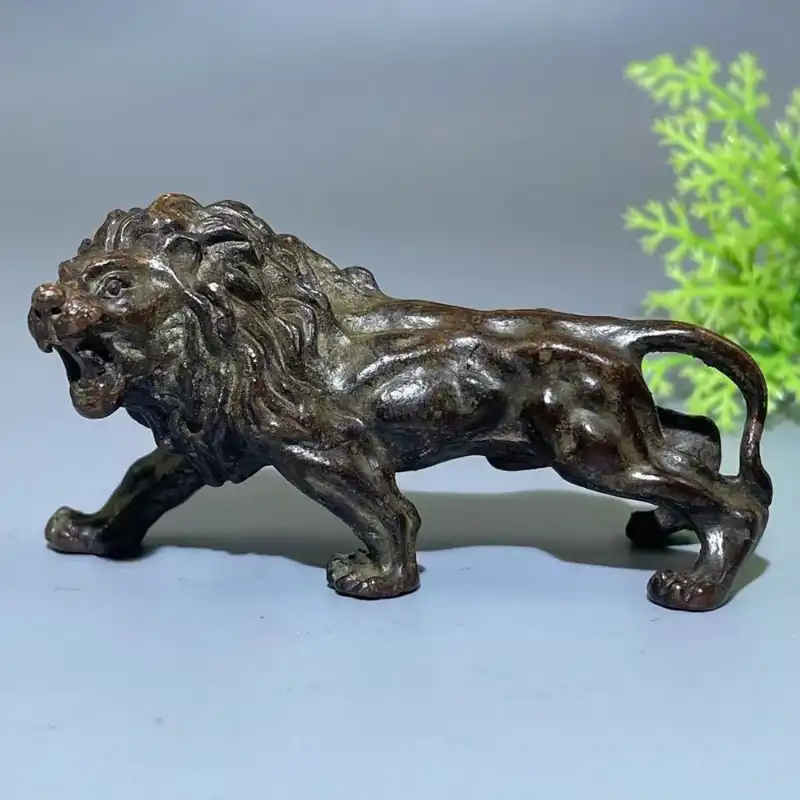 Small bronze lion ornament displaying detailed craftsmanship and aged finish for home decor.