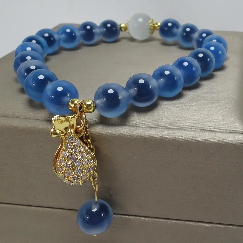 Elegant money bag pendant detail on handmade blue agate bead string bracelet.