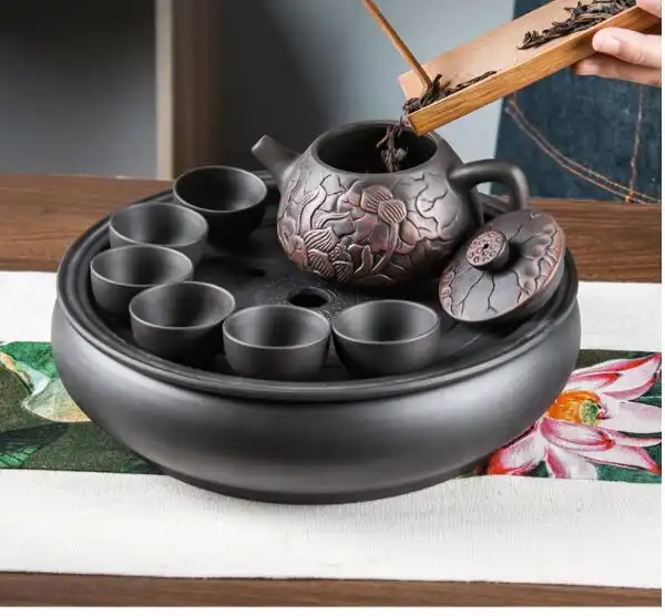 Black mud Yixing teapot spout and handle detail with elegant lotus motif carved surface texture.