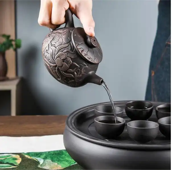 Folk artist handcrafting authentic Yixing teapot with delicate lotus pattern carving technique.