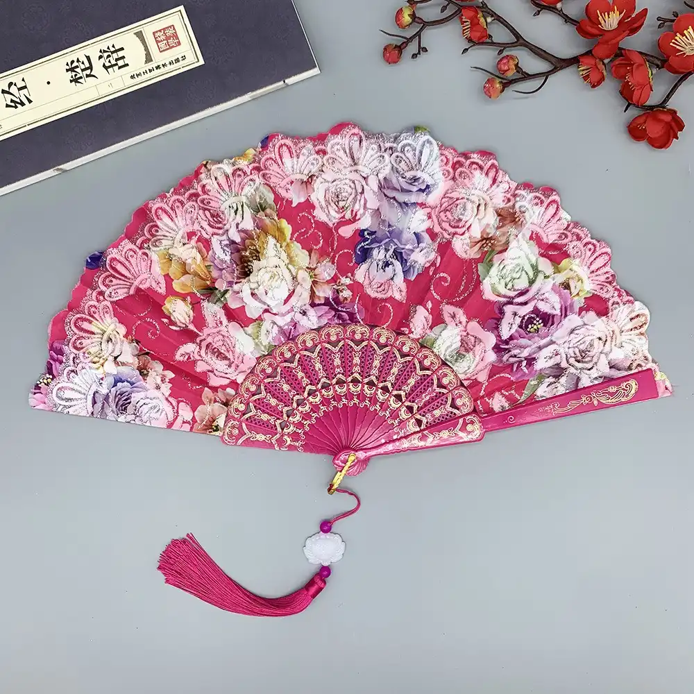 Gold foil rose pattern detail on silk fan showing light reflection and visual impact.