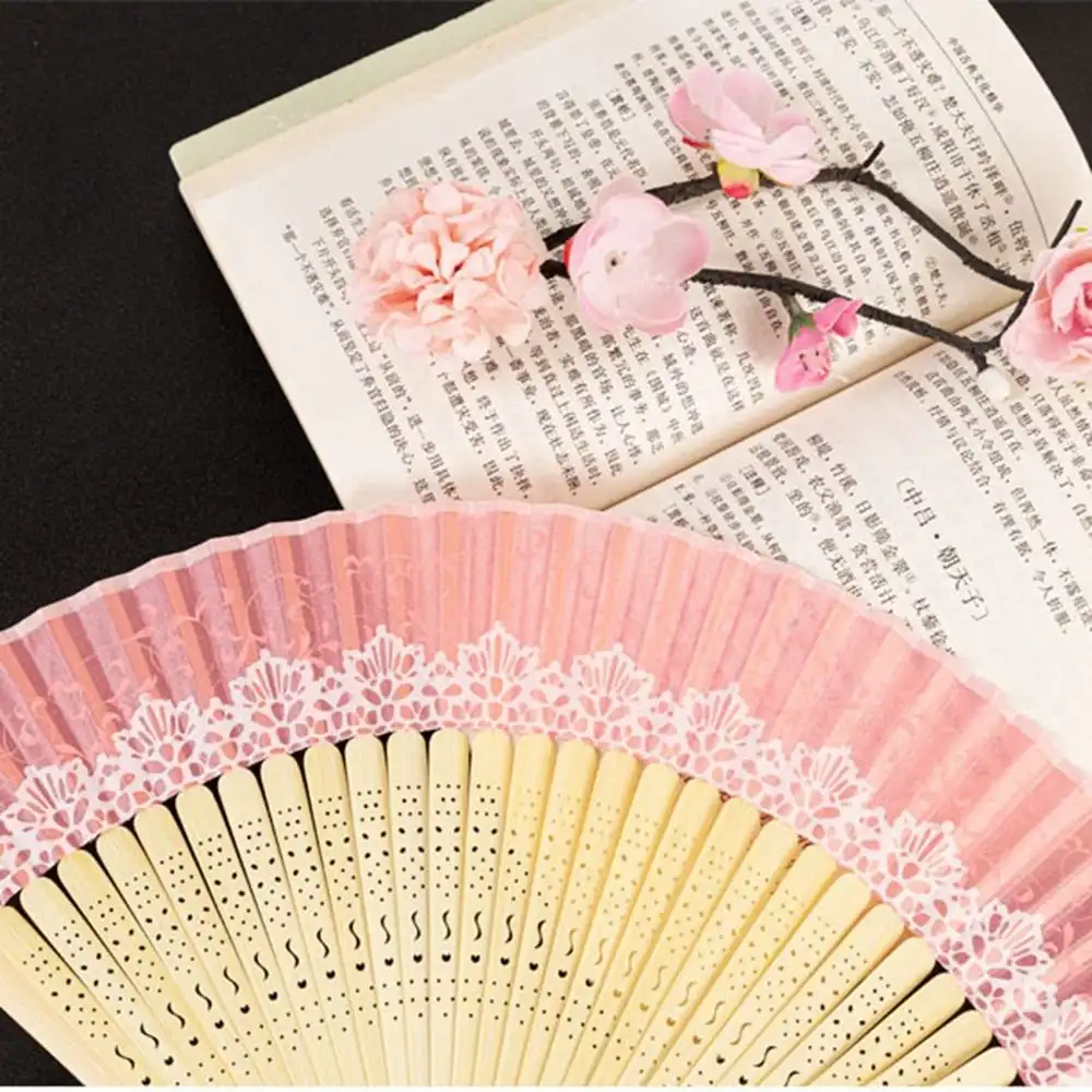 Japanese bamboo silk folding fan with decorative tassel displayed open showing intricate lace pattern.