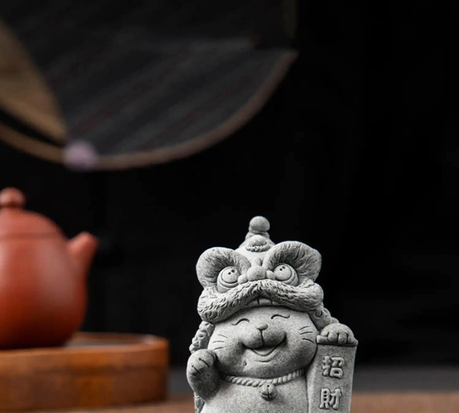Stone cat tea pet placed on traditional tea tray with teapot and cups during ceremony.