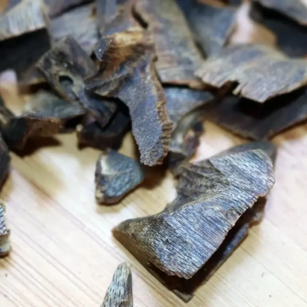 ​​Close-up detail of high-grade underwater oud chips displaying 90% resin content and authenticity.